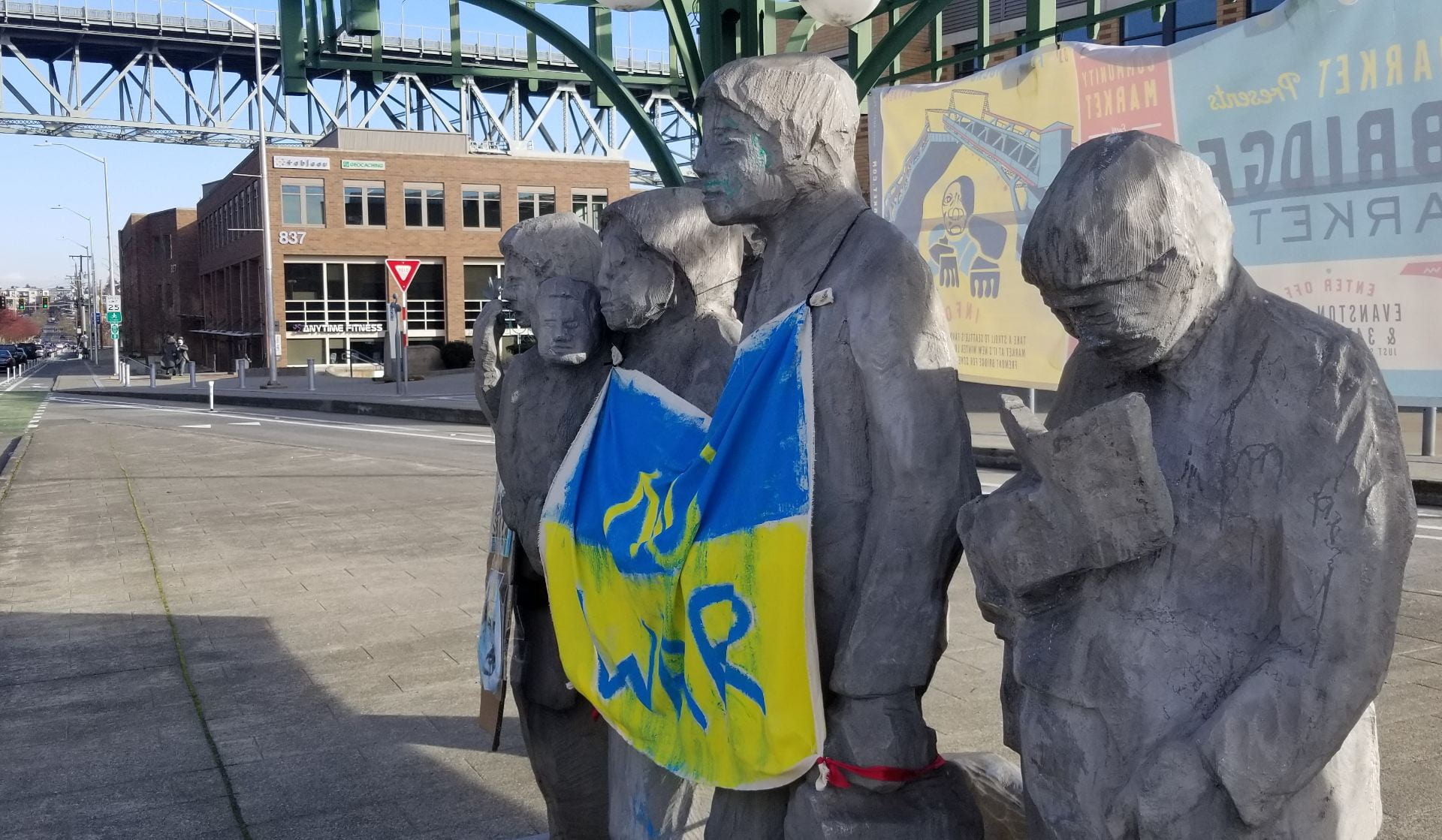 A Ukrainian flag reading No War is draped over the Waiting for the Interurban statue in Seattle's Fremont neighborhood