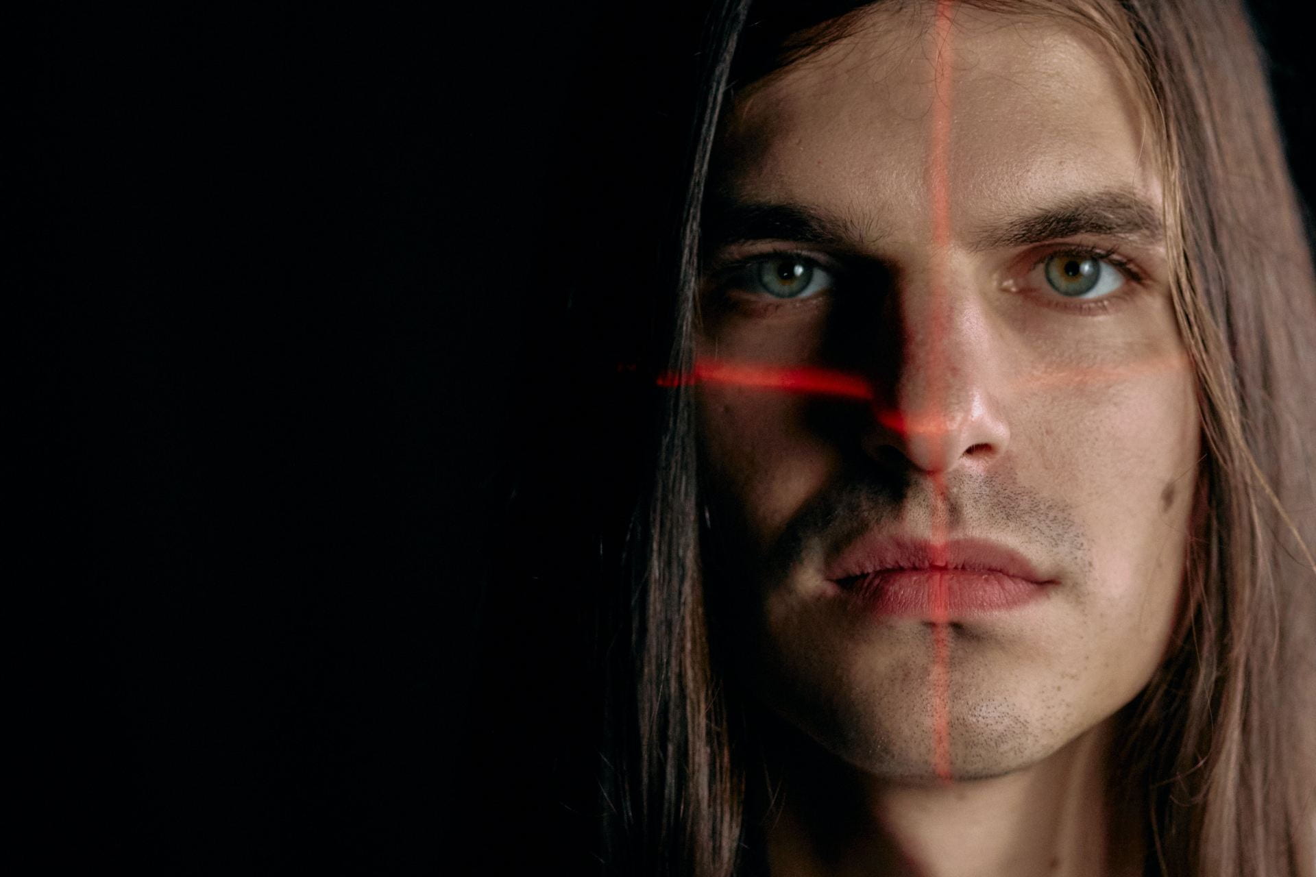 Facial recognition stock image featuring man with red scanning lights on his face.